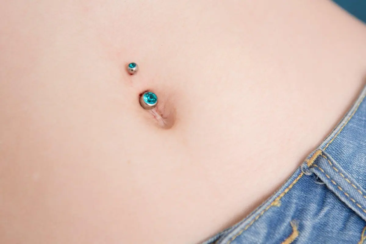 Frisch gestochenes Bauchnabelpiercing mit türkisfarbenem Schmuck