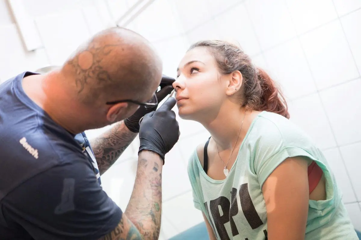 Daniel Graf zeichnet die Position eines Nasenpiercings an