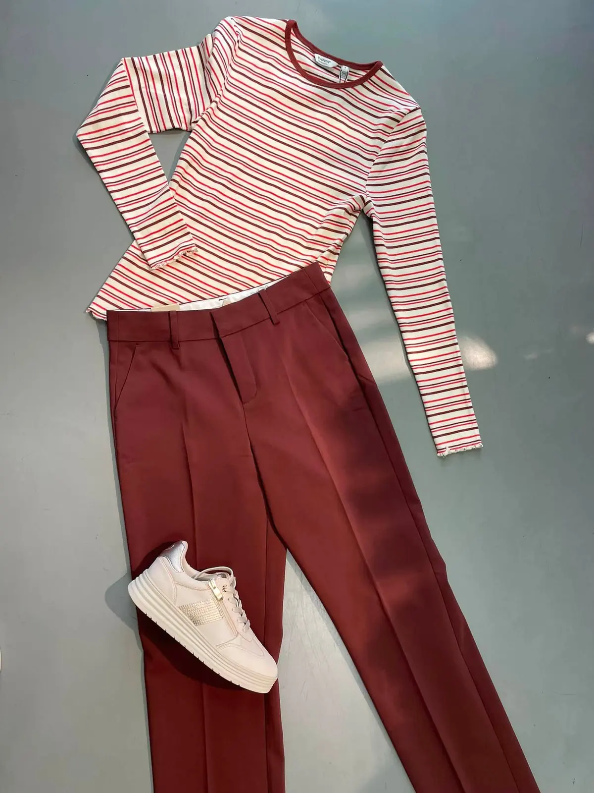 Streifenshirt mit bordeauxroter Stoffhose und Sneakern